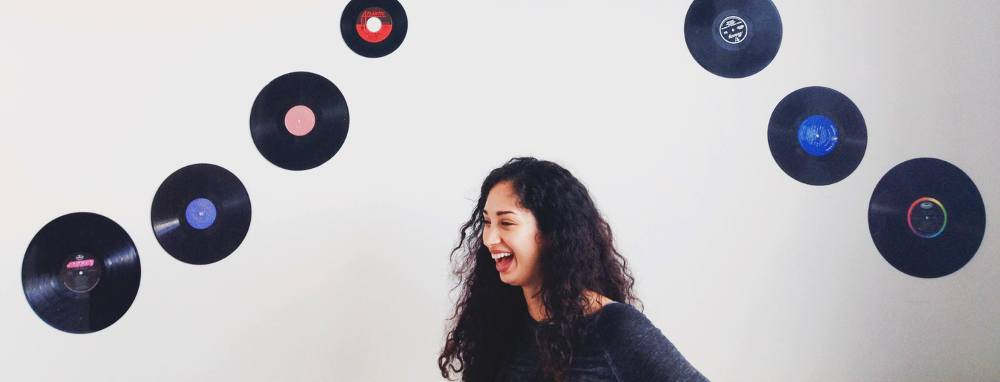 Junge frau lacht vor wand mit schallplatten rockstar mitarbeiter