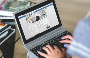Small frau mit laptop auf den knien ist bei facebook auf jobsuche