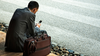 Middle r ckansicht von sitzendem mann im anzug mit telefon in der hand   telefoninterview