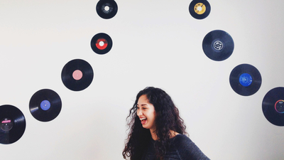 Middle junge frau lacht vor wand mit schallplatten rockstar mitarbeiter