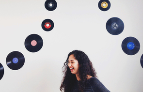 Small junge frau lacht vor wand mit schallplatten rockstar mitarbeiter